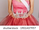 Closeup of a woman in tulle dress, holding a diamond crown. Beauty contest winner.