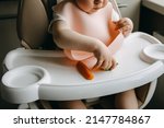 Small photo of Baby sitting in high chair, with a silicone bib, eating vegetables.