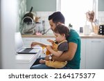 Small photo of Dad working on laptop with child sitting on his lap