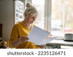 Small photo of Senior woman filling out financial statements