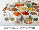 Colorful herbs and spices for cooking dishes. Indian and Asian spices On white stone background closeup