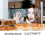 Woman in scarf looking at the bakery window full of different pieces of tarts