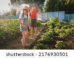 Small photo of Sibling children frolic splashing with a water hose in the backyard in the garden on summer holidays in the village on a hot day. Friends fun