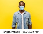 Small photo of Portrait of serious self-assertive handsome man with medical mask with rolled up sleeves looking smart and professional, freelancer or employee. indoor studio shot isolated on yellow background