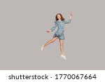 Small photo of Happy delicate girl in vintage ruffle dress levitating with ballet dance move, hovering in mid-air and smiling joyfully, jumping trampoline, flying up. indoor studio shot isolated on gray background