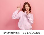 Small photo of Portrait of bossy curly-haired teen expressing disrespect, showing L finger sign to camera, loser or lame gesture, accusing for failure. Indoor studio shot isolated on pink background