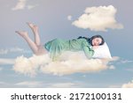 Small photo of Relaxed girl in ruffle dress levitating in mid-air, sleeping on stomach lying comfortable cozy on pillow, keeping eyes closed, watching peaceful dream. collage composition on day cloudy blue sky