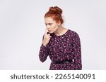 Small photo of Portrait of ginger woman wearing dress pointing nose doing lie gesture, suspecting trickster in falsehood, her look expressing distrust, disbelief. Indoor studio shot isolated on gray background.