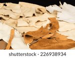 Small photo of Assorted pieces of buckskin; doeskin; rawhide; and cured leather against black background.