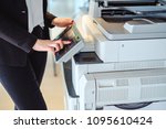 Woman standing and pressing button on a copy machine in the office