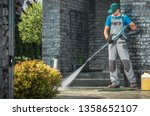 Driveway Pressure Washing. Caucasian Worker Cleaning Area in Front of the House.