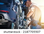 Small photo of Caucasian Towing Worker Fastening Broken Vehicle with Tie Down Straps. Professional Roadside Assistance and Breakdown Coverage Services. Automotive and Transportation Industry.