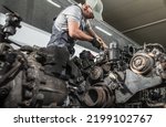 Caucasian Professional Truck Mechanic Rebuilding Heavy Duty Truck Diesel Engine. Automotive Industry Theme.