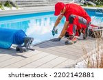Small photo of Professional Swimming Pools Worker Finishing Composite Outdoor Pool Deck Installation. SPA Industry Theme.