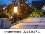 Small photo of Closeup of Garden Bollard Lamp Installed Along the Walkway in Landscaped Backyard Garden. Evening Time. Outdoor Lighting Theme.