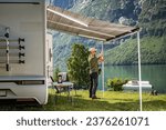 Small photo of Caucasian Tourist Extending Camper Van RV Awning. Setting Up Scenic Campsite.