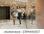Shot of two attractive girlfriends smiling while walking with shopping bags in the city mall during the day.