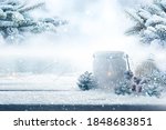 Christmas decoration on wooden table with fir branchs in a snowy garden. Winter background for christmas and advent concepts with space for text.