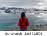The girl stands with her back against the background of a melting glacier. Iceland.
