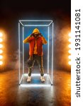 Small photo of Stylish rapper poses in illuminated cube