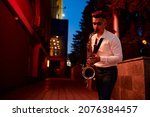 Young saxophonist plays the sax on street at night