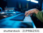 Small photo of Closeup of keyboardist musician in neon light recording studio