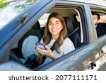Small photo of Happy female driver smiling and making eye contact while accepting a passenger's ride on the carpool service app