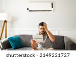 Expensive bills. Stressed latin man looking at the high electricity bill because of the air conditioning