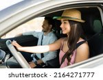 Excited latin woman smiling while driving with her partner during the weekend for a relaxing vacation