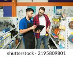 Young man working in customer assistance at the hardware store and talking with a client shopping at the hardware store