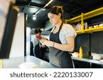 Woman stall vendor at the food truck checking the customers orders on the delivery app on the smartphone