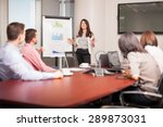 Beautiful young Latin brunette giving a business presentation to some of her clients in a meeting room