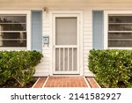 Small photo of White front door of a house that is surrounded by a white picket fence and elegant landscaping.