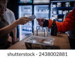 Small photo of Riga, Latvia - March 3, 2024 - A customer makes a payment using a card reader at a venue, possibly at a padel tournament concession stand.
