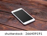 White smart phone with blank screen lying on wooden table