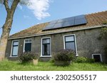 Small photo of Older renovated small rural house in a green environment with solar panels on the roof in the village of Warns in the Netherlands. Old-fashioned and modern at the same time. Sustainable energy