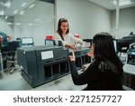 Bank employees using money counting machine while sorting and counting paper banknotes inside bank vault. Large amounts of money in the bank