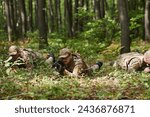 Small photo of Elite soldiers stealthily maneuver through the dense forest, camouflaged in specialized gear, as they embark on a covert and strategic military mission
