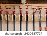 Small photo of Array of red bar clamps on a woodshop rack.