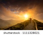 Woman standing on a beautiful path with arms open at the sunset