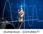 Small photo of Close up of businessman hand with pen pointing at abstract glowing mathematical formula graph on blue background. Equation, digital data and mathematics app concept