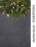 Small photo of Christmas winter & New Year background border with snow covered fir, mistletoe, cedar, opine cones & ivy leaves on grunge grey background with copy space.