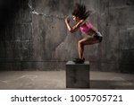 Fit young woman box jumping at a crossfit style on gray background. Fitness,  functional, training, and lifestyle concept