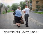 Small photo of Young helper male guy go teach preach hold book look stand tired weak adult age grandma lady. Ask offer share hard aid care don't Jesus Christ church public social human walk culture back scene view