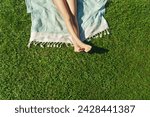  Child feet on green grass, barefoot little girl on meadow. Sunbathing on the green grass - lifestyle, concept of grounding and connecting with nature.