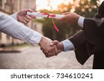 Cropped image of graduate in academic dress taking his diplomas and shaking hand