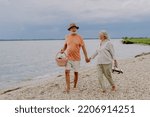 Senior couple walking with picnic basket near the river.