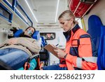 Small photo of Rescuer taking care of patient, writing her diagnosis.