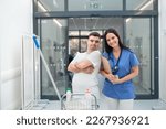 Young man with down syndrome working in a hospital as cleaner, talking to nurse, having fun. Concpet of integration people with disability into society.