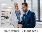 Small photo of Pharmaceutical sales representative talking with doctor in medical building, presenting new medication on tablet. Hospital director, manager in modern clinic with surgeon.